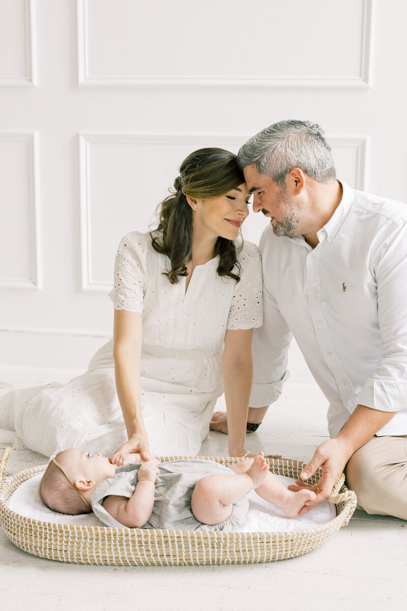 Parents kneeling with their toddler during an indoor lifestyle family photo session.