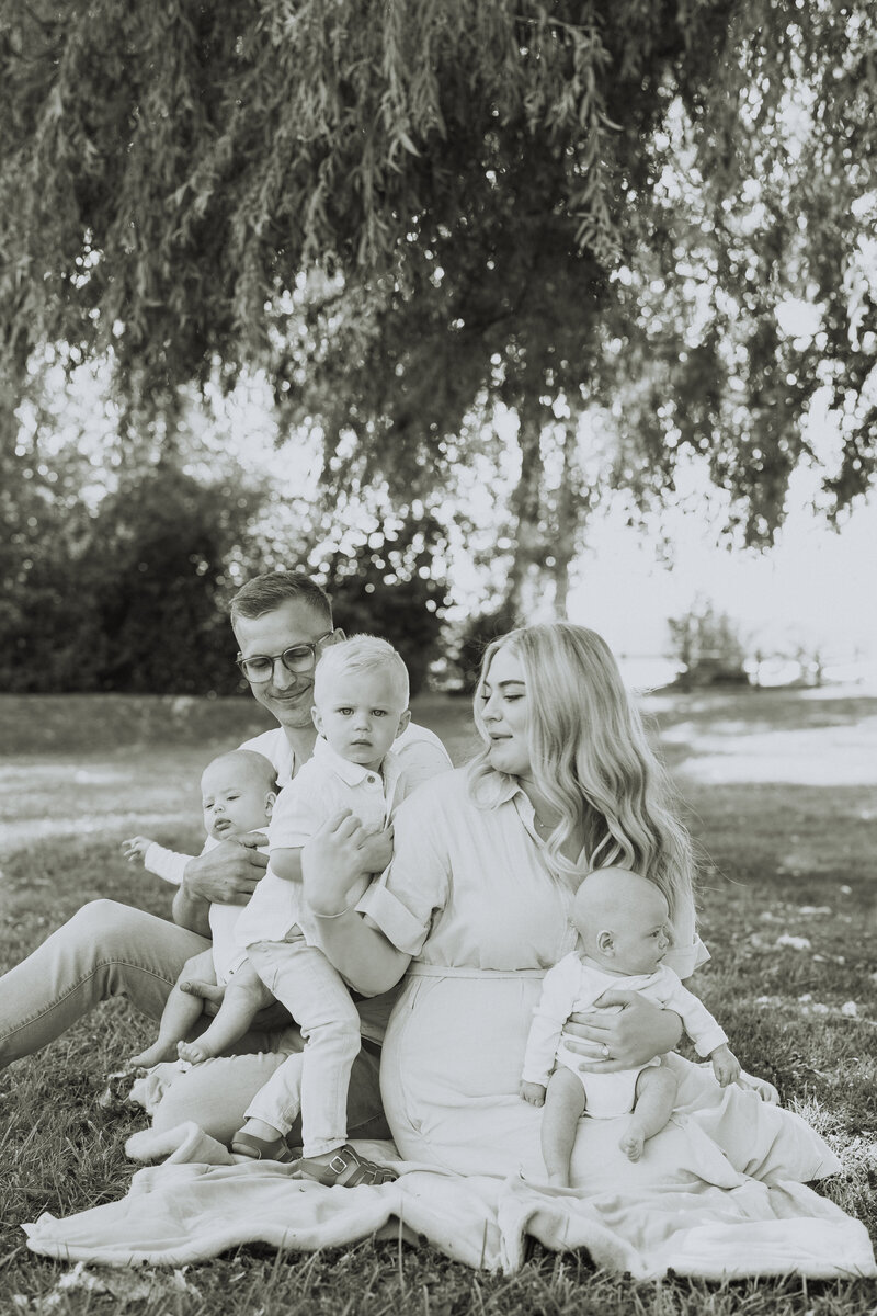 Black and white photo of a family sitting on the ground taken by an abbotsford family photographer
