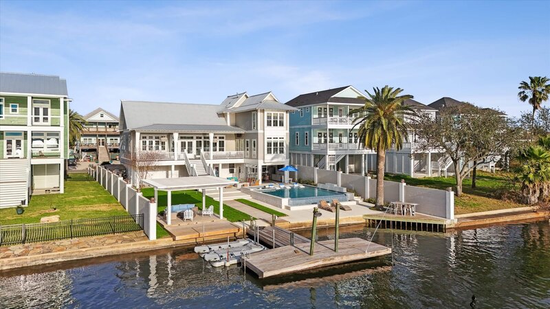 Dillard Signature Living home showcasing modern pool design, outdoor lounge, and waterfront views framed by palm trees.
