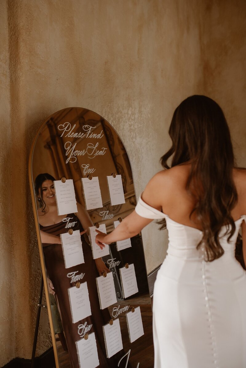 Bride reading seating chart with white escort cards attached