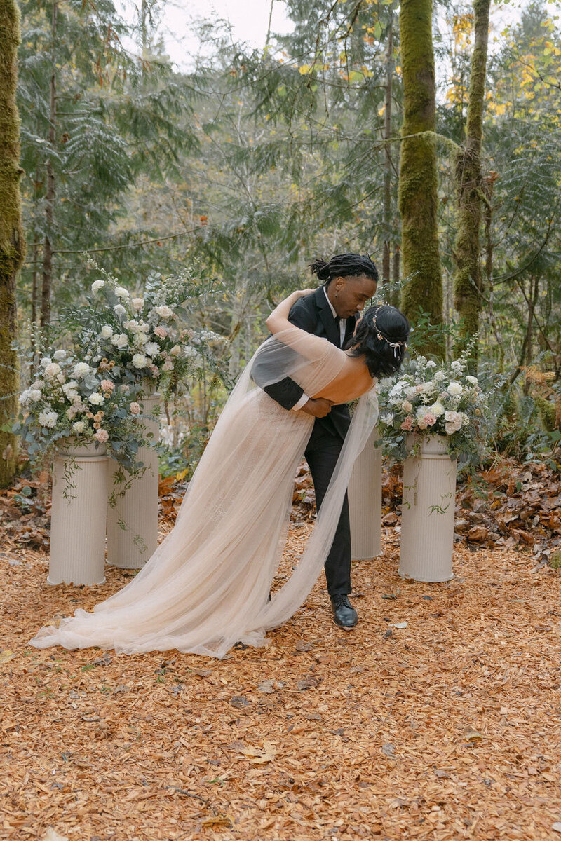 Couple sharing a romantic dip surrounded by lush forest florals