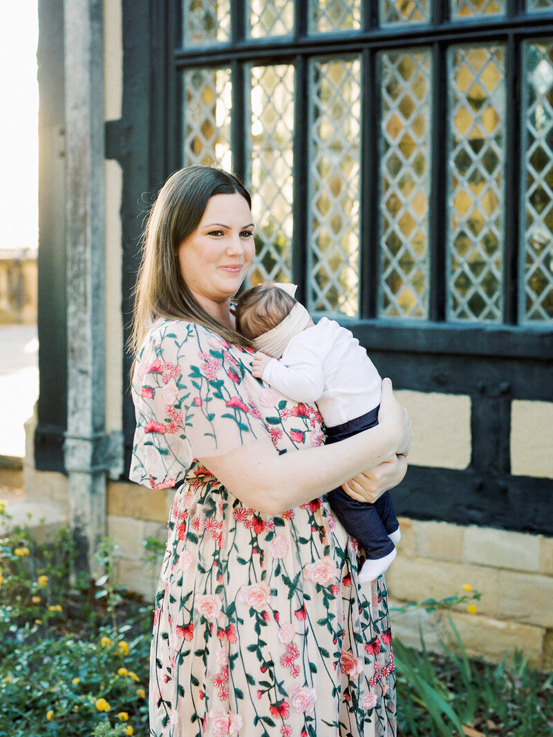 A mother looking into the distance while holding her baby by Katie Stansfield Photography, a Richmond family photographer.