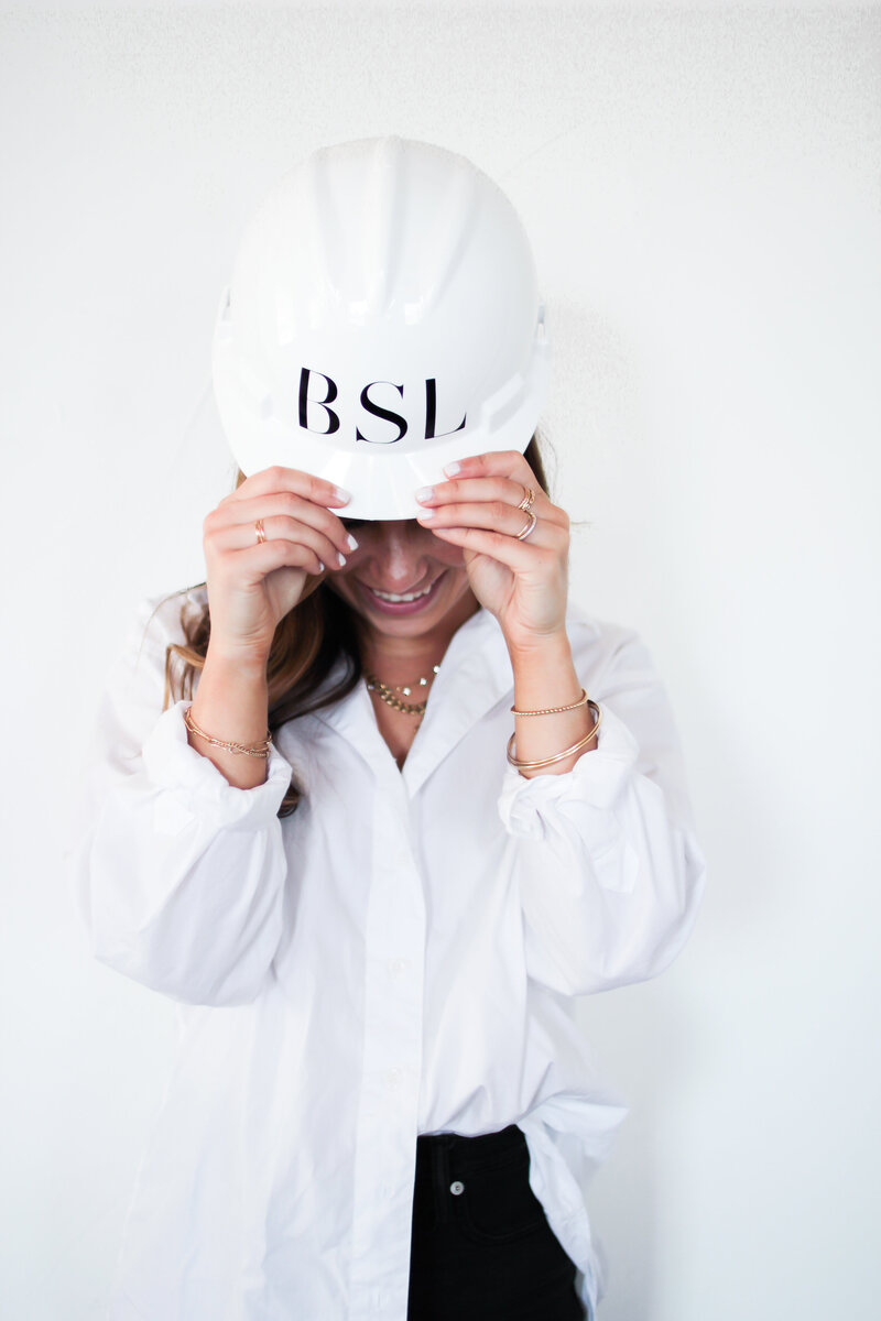 woman holds brim of hardhat