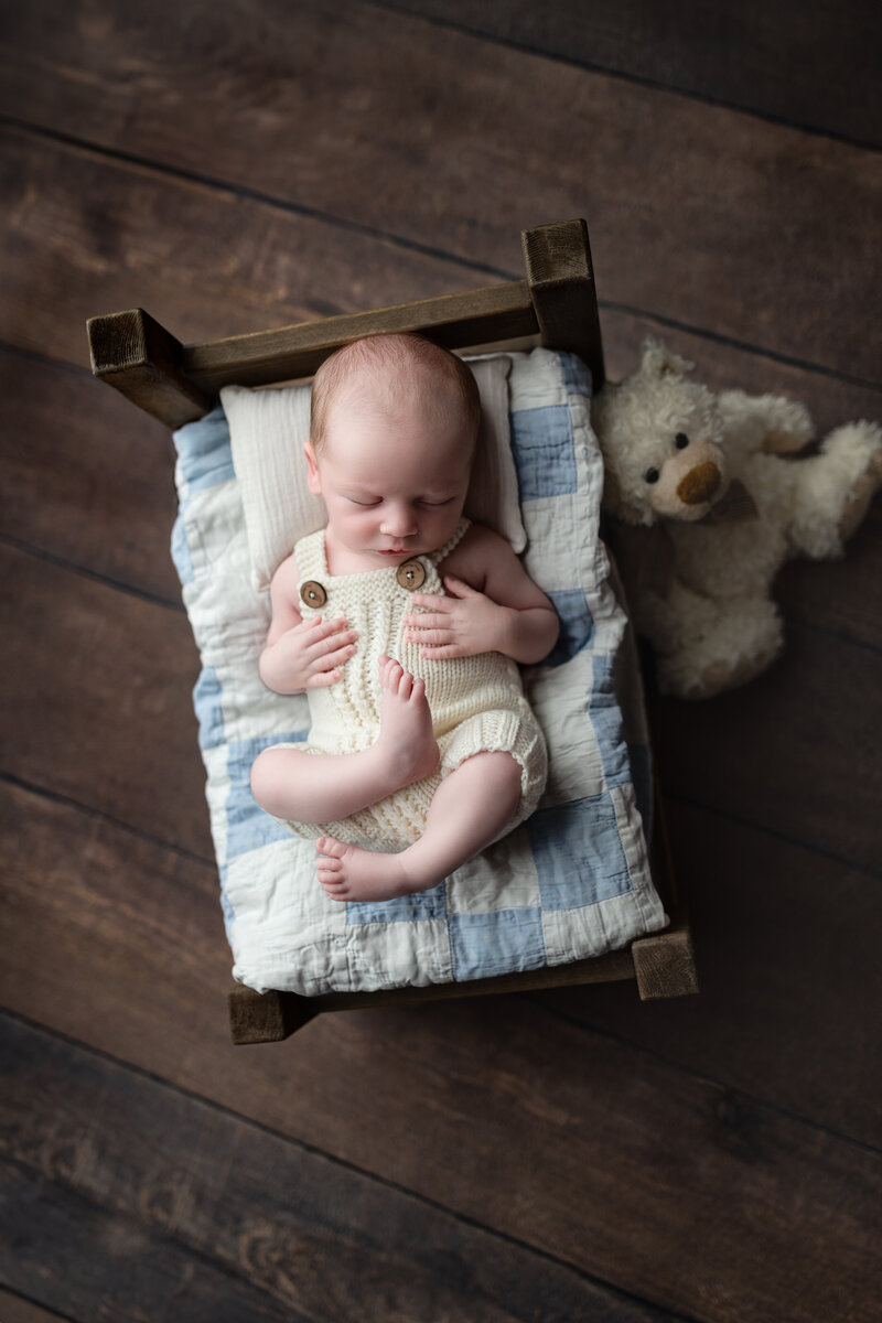 A classic newborn boy setup featuring textures, quilts, and timeless sleepy charm.