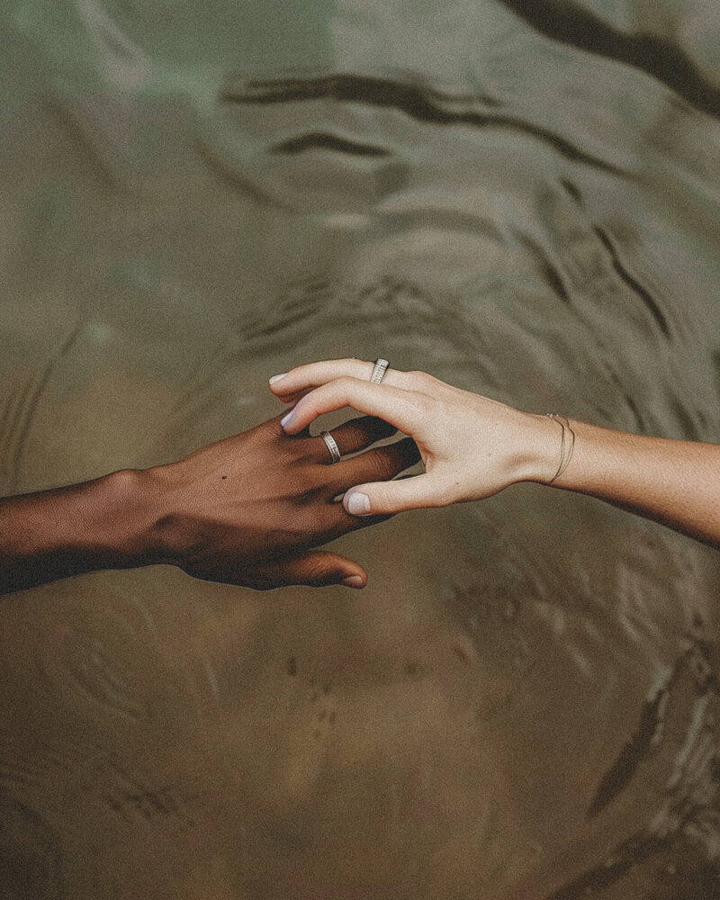 Two hands reaching gently across water, symbolizing emotional safety, trust, and social justice connection in trauma and couples therapy with Jessie Withers, Los Angeles