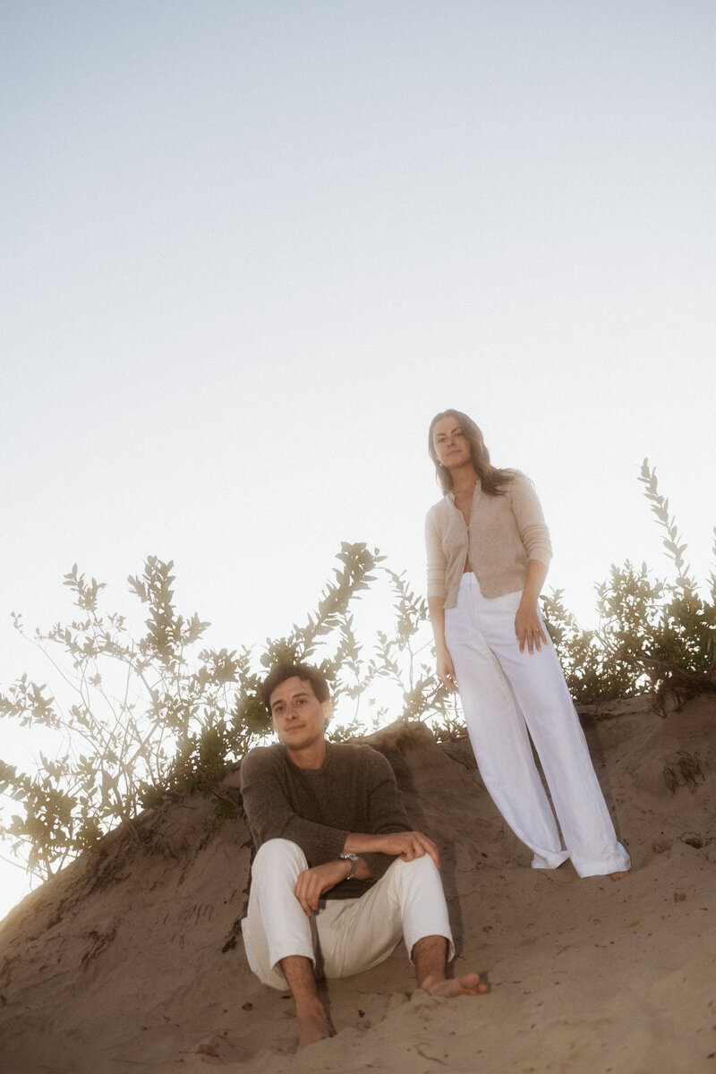Editorial portrait of couple standing on sand dunes for engagement photos