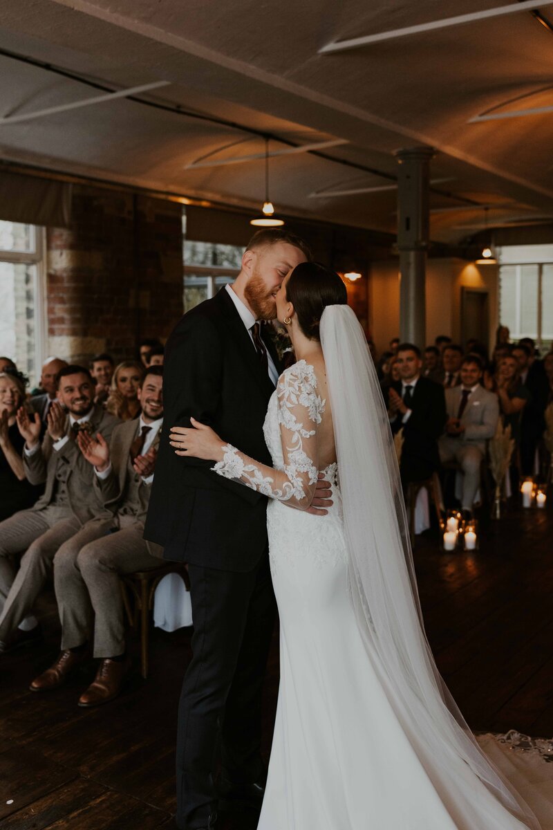 Black and White cinematic shot of newly married couple sharing a joyous and tender first kiss as husband and wife at Davenport House