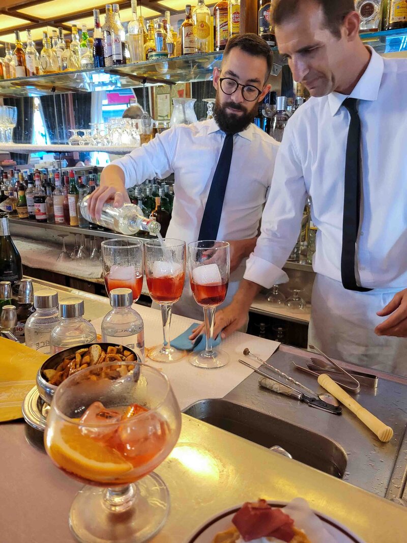 Barmen in white shirts and ties preparing negronis and Aperol spritzes at Bar Basso in Milan ©Stephanie Dosch | theViatrix Luxury Travel