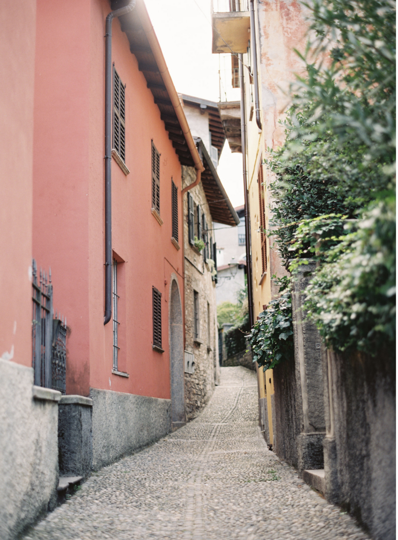 Narrow walkway through shaded buildings in Italy.