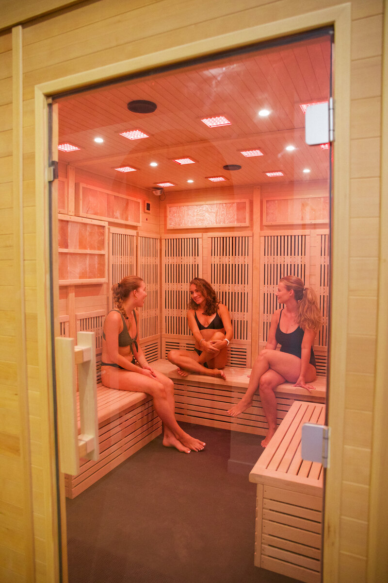 A group of new friends meeting, laughing and chatting in an infrared sauna.