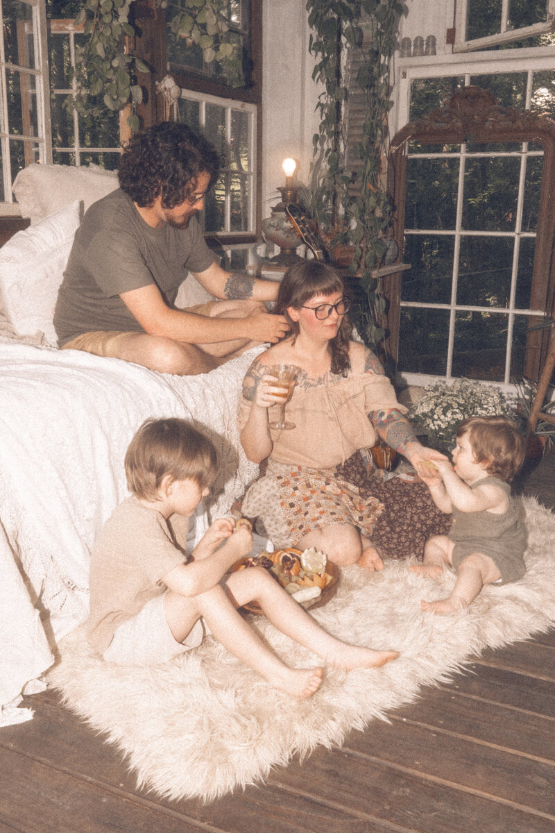 A family of four sitting on a blanket snacking in Das Hinterhaus.