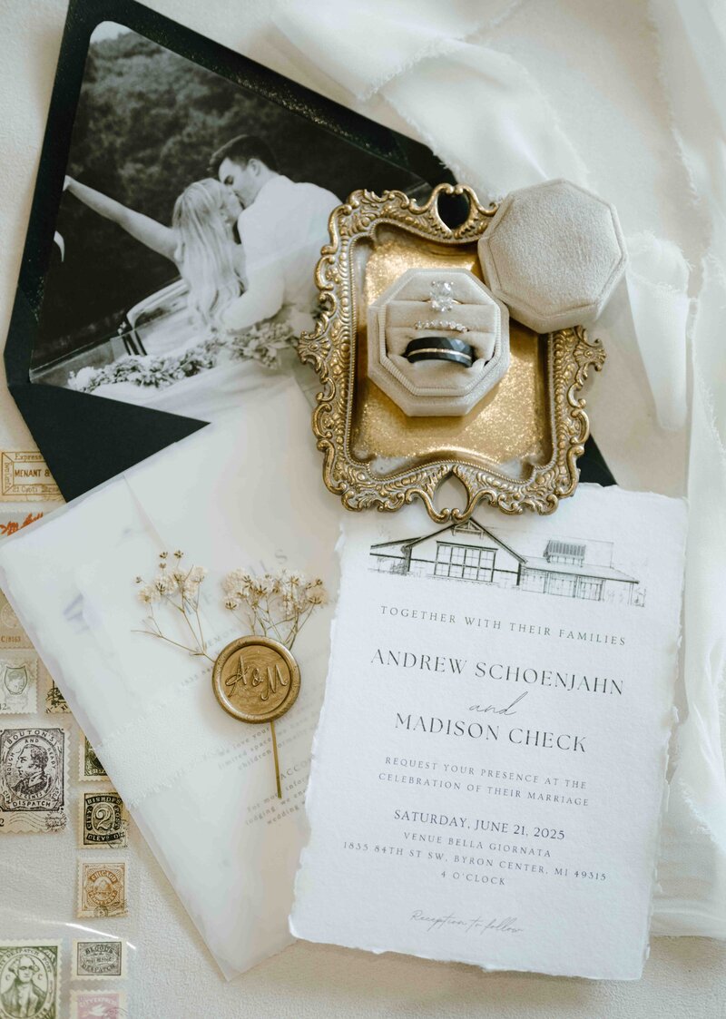 A flat lay photo of wedding invitations and luxury wedding details in black white and gold colors