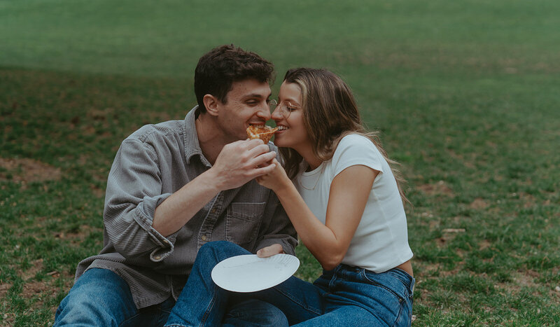 couple eating pizza in the grass during NYC couples photos, captured by Elsie Goodman, an NYC engagement and couples photographer