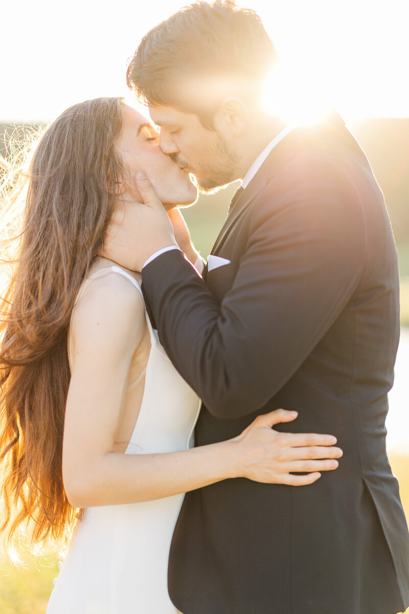 bride and groom kissing as sunlight shines on them