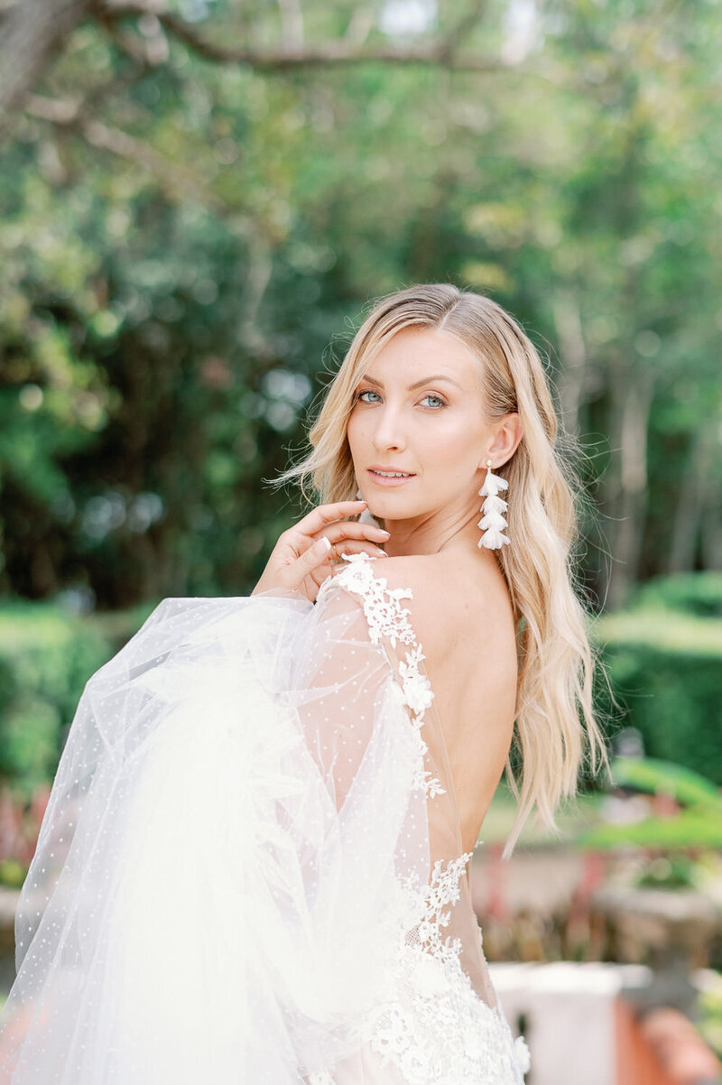 Stunning bride in high end wedding gown looks over her shoulder at the camera in Miami