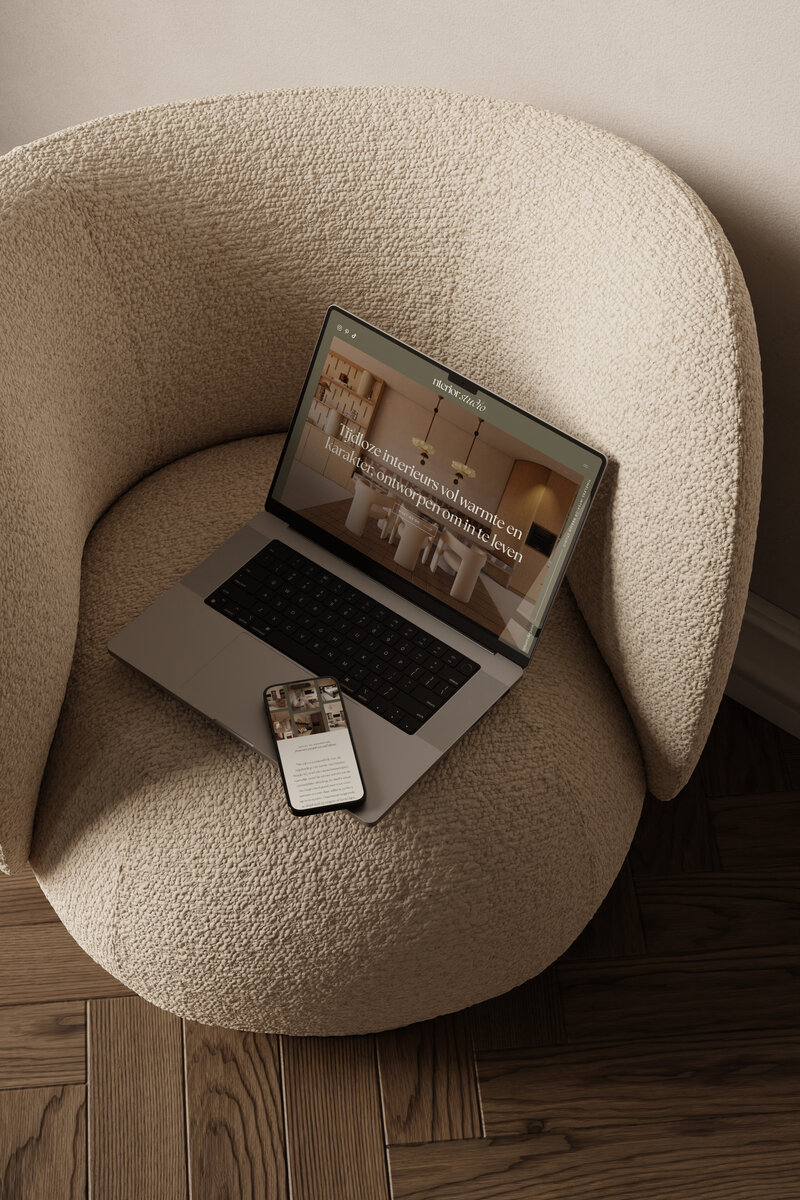 Laptop op houten tafel met open website van Studio Lave, getoond is de pagina over interieurontwerp met warme natuurlijke kleuren