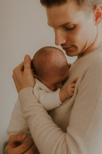 photo naturelle de bebe blotti dans les bras de son papa