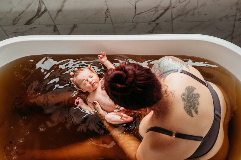 Mother resting in tub after birth holding baby— intimate postpartum Fresh 48 session in Fort Worth by Poppy + Blue Photography