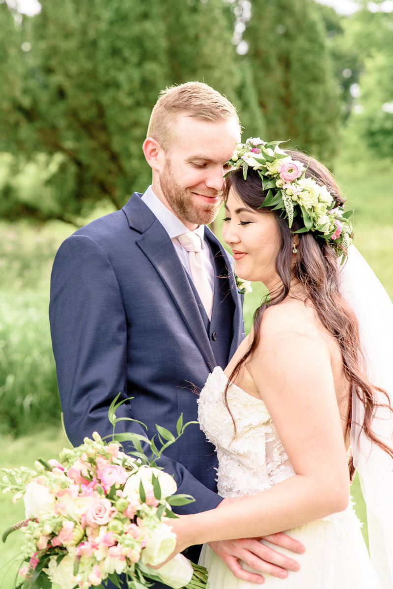 A bride in a floral wreath poses with her husband.