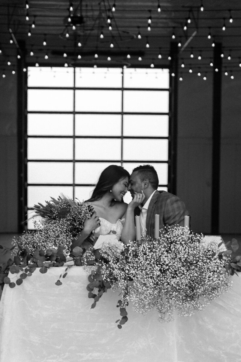 Couple nuzzling each others foreheads, black and white, at that gorgeous table.