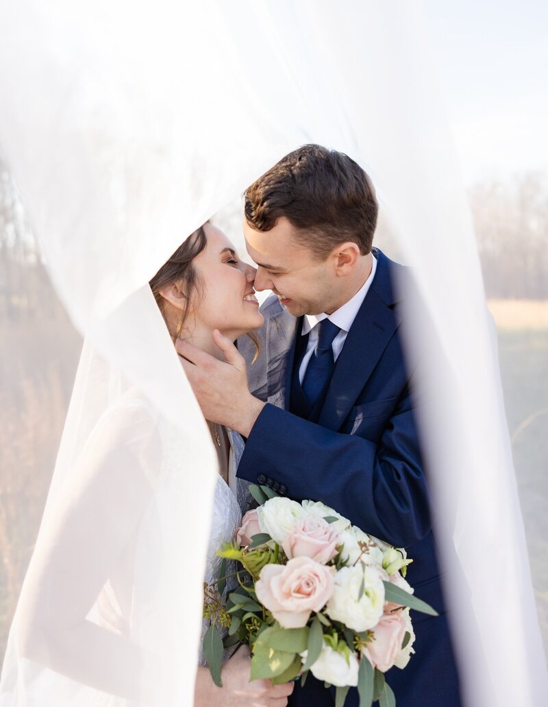 bride and groom kissing underneath the veil