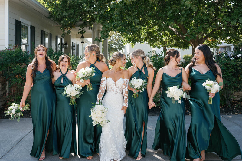 bride posing with her bridesmaids in forest green dresses
