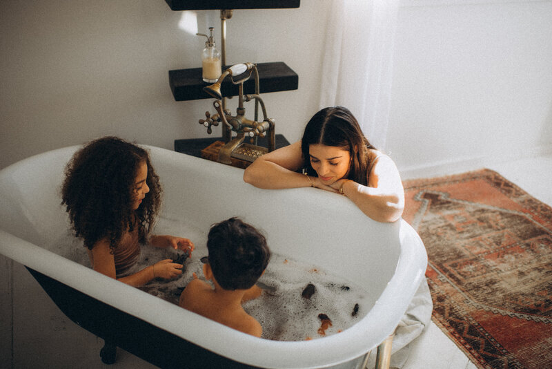 Mom watching her kids play with toys in the bath in their Scottsdale home