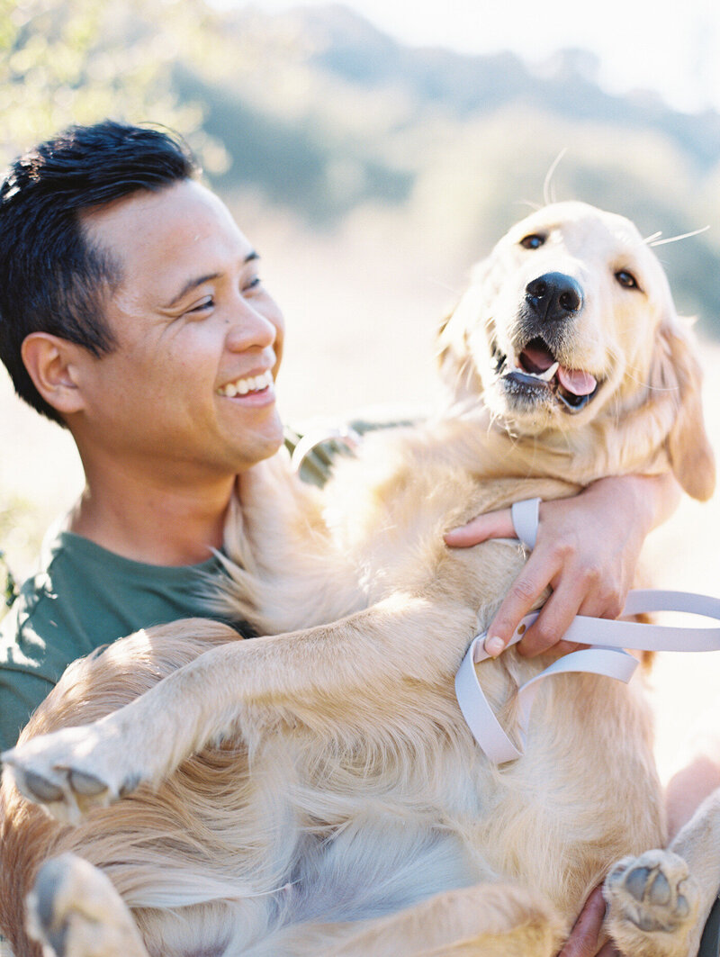 groom looking at his large dog who he is holding and smiling
