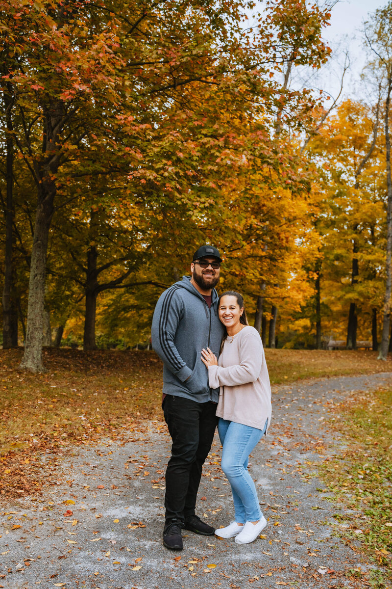 man and woman standing outside on dirt road under autumn trees
