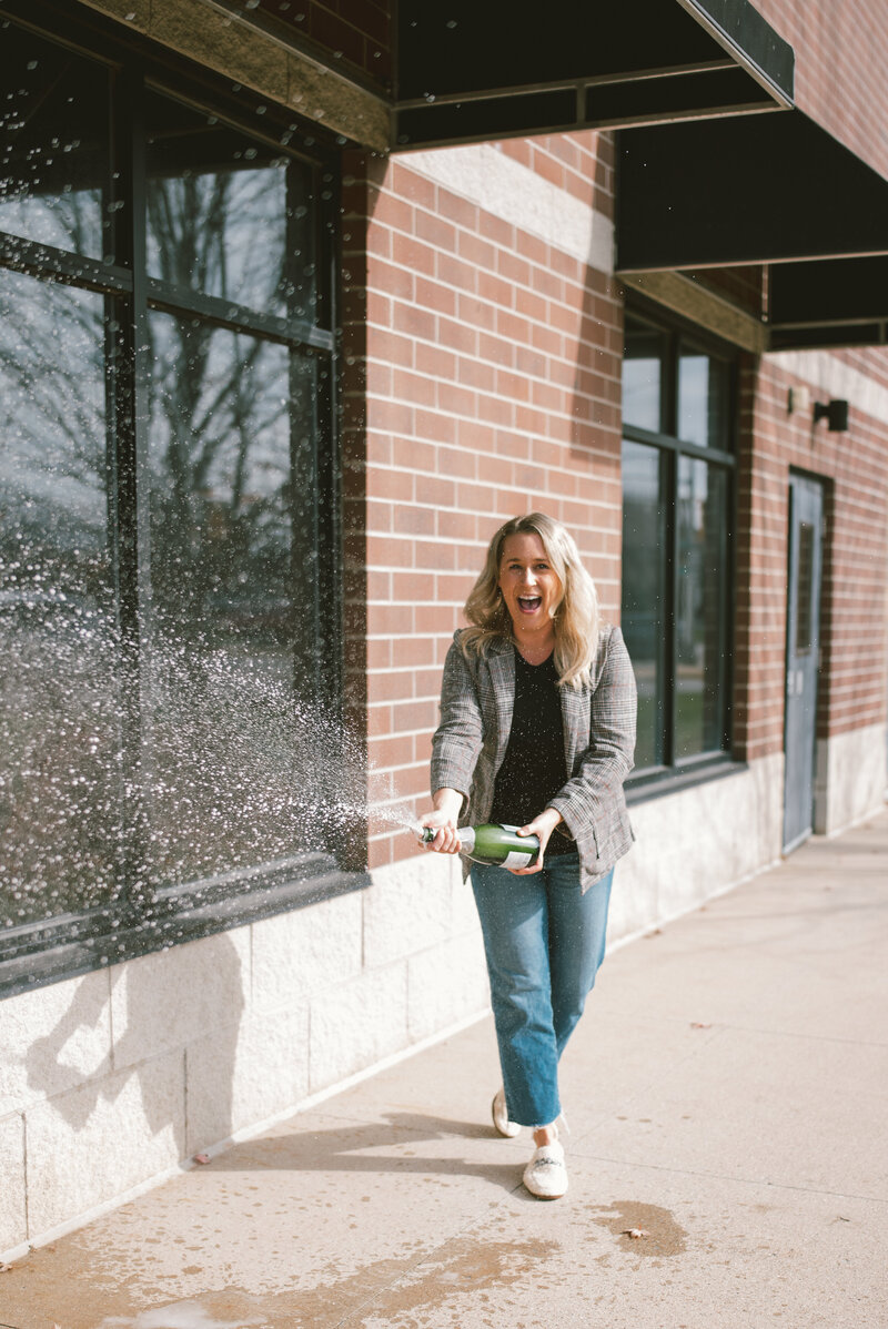 Sarah Kaetterhenry downtown Stevens Point popping champagne in celebration