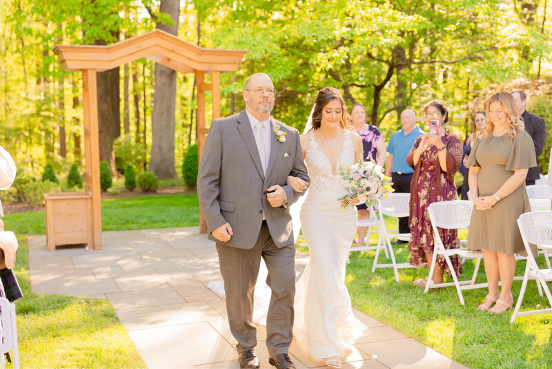 A wedding party celebrates the bride and groom with Gramercy Mansion Wedding Photographer in the gardens.