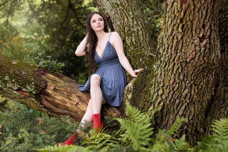 Fuquay Varina High School Senior on a tree surrounded by ferns.