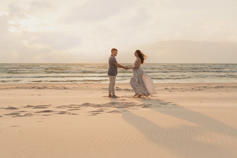 Expecting couple dancing by the shoreline photographed by Michigan maternity photographers