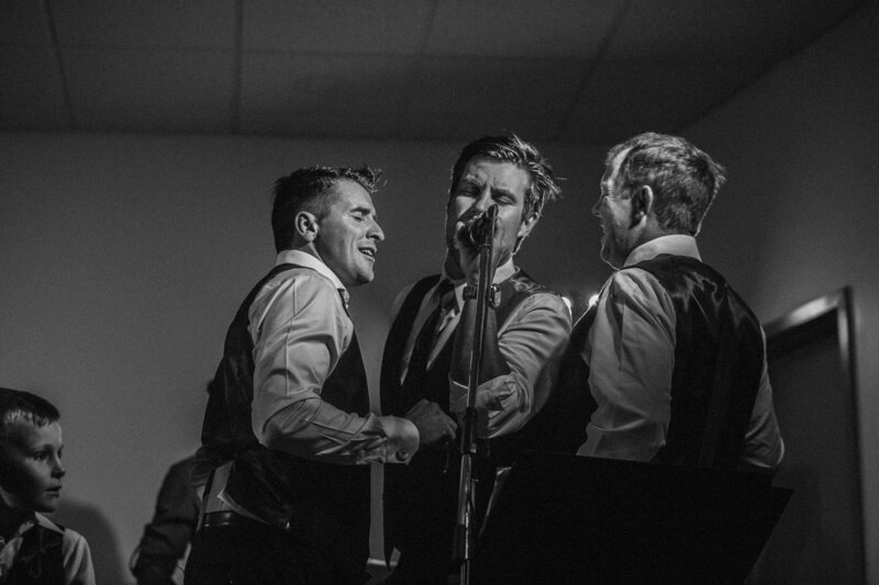 3 groomsmen singing at wedding