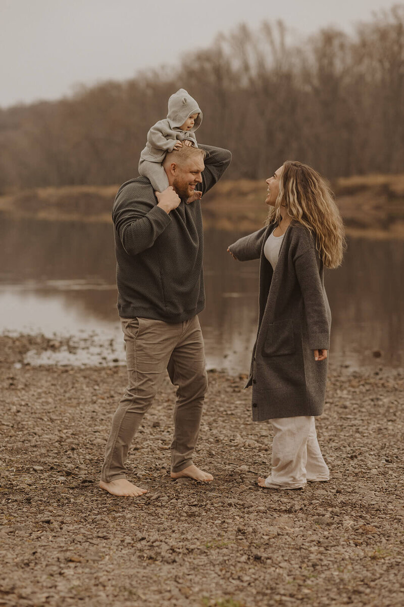 Minneapolis photographer dances with her husband and baby on the banks of St. Croix, Minnesota