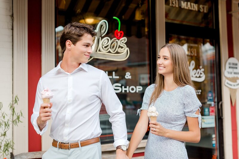 Engaged couple walk down a Stillwater, Minnesota street holding ice cream cones for engagement photo session.
