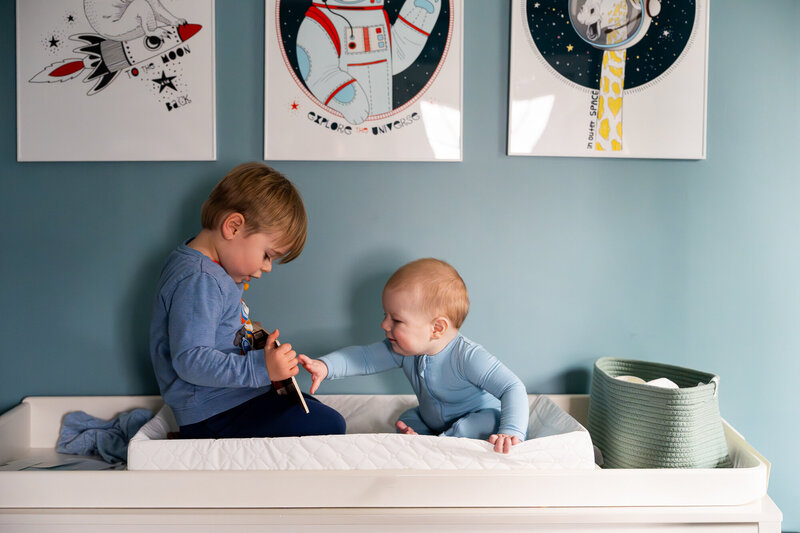 Toddler boy reading to baby brothr