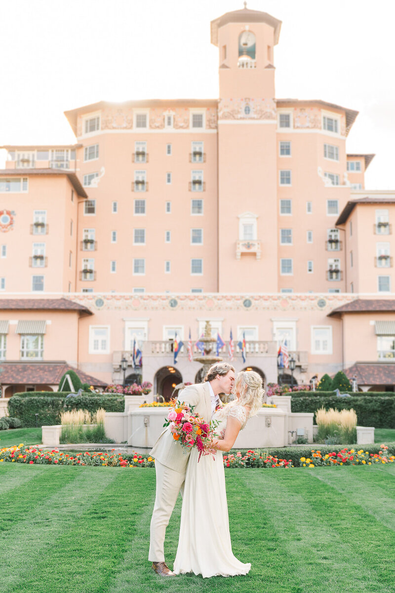 Newly married couple kissing in front of the iconic Broadmoor Hotel in Colorado Springs.