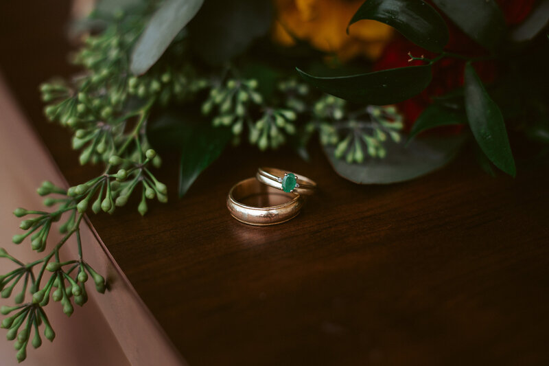 wedding rings on table next to green leaves