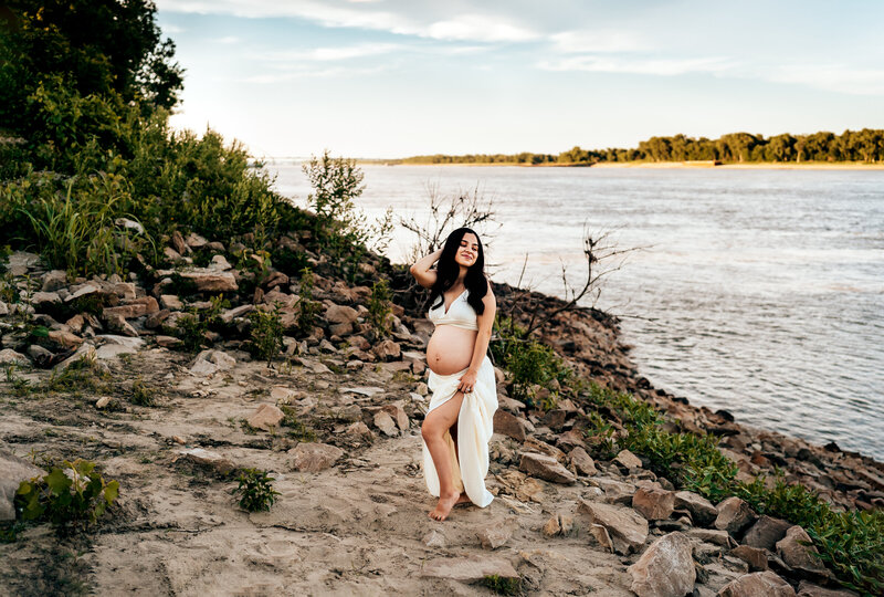 pregnant woman standing near the river with her hand on her head