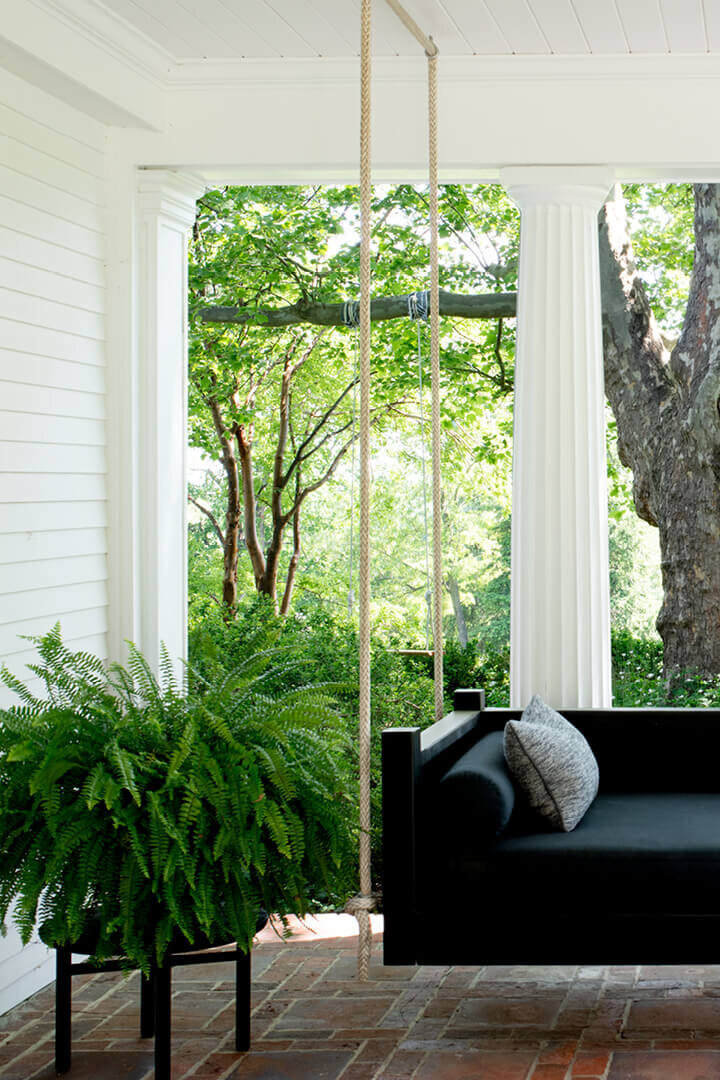 Interior decorators update a historic Concord home with a black daybed, blending original architecture with modern outdoor living style. 