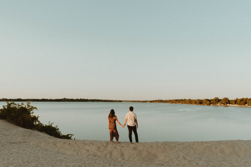 couple holding hands overlooking lake