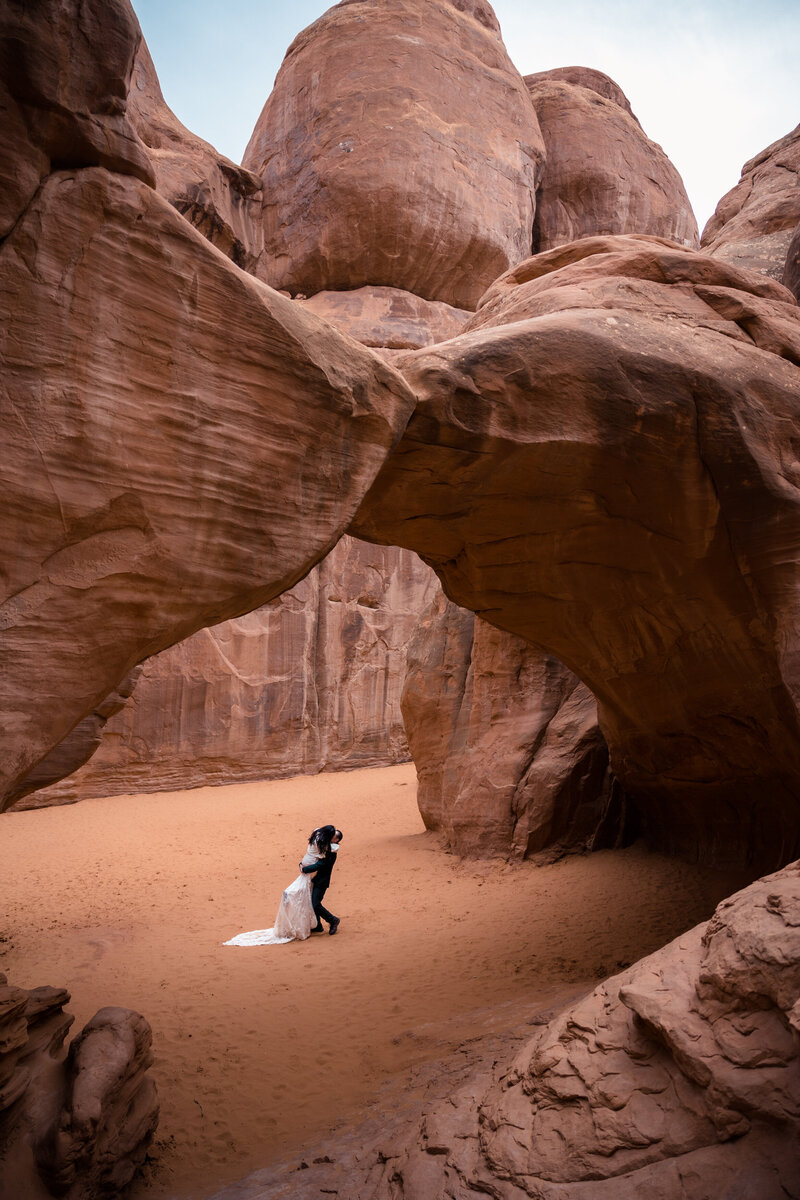 couple kissing under arch in utah