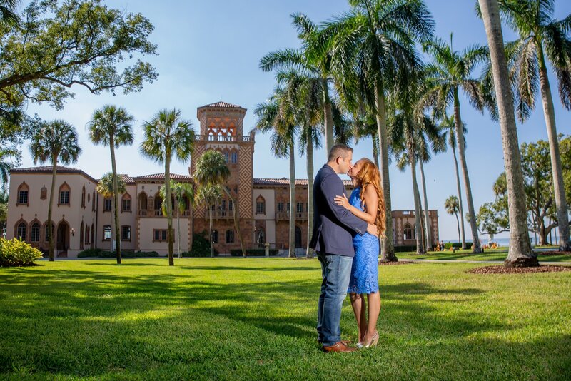 Engagement photo of couple kissing on the lawn in front of the Cad'a'zan in Sarasota, Fl