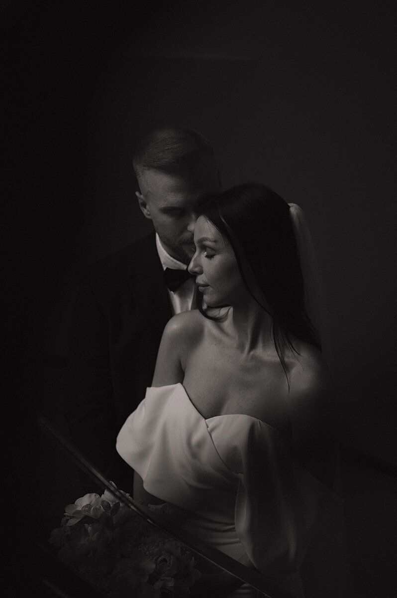 Svartvitt bröllopsporträtt på brudpar, står nära varandra i trappan.