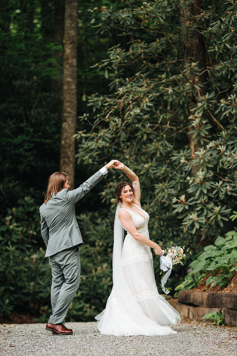 groom twirling a bride under trees