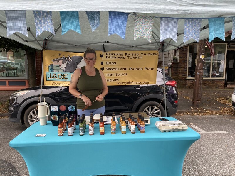 A flower vendor offers a selection of bright, fresh flowers at the Chestertown Farmers Market, enhancing the market's charm.