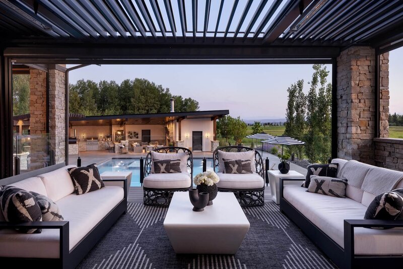 Outdoor black and white furniture overlooking a pool and poolhouse with a suncoast enclosure. 