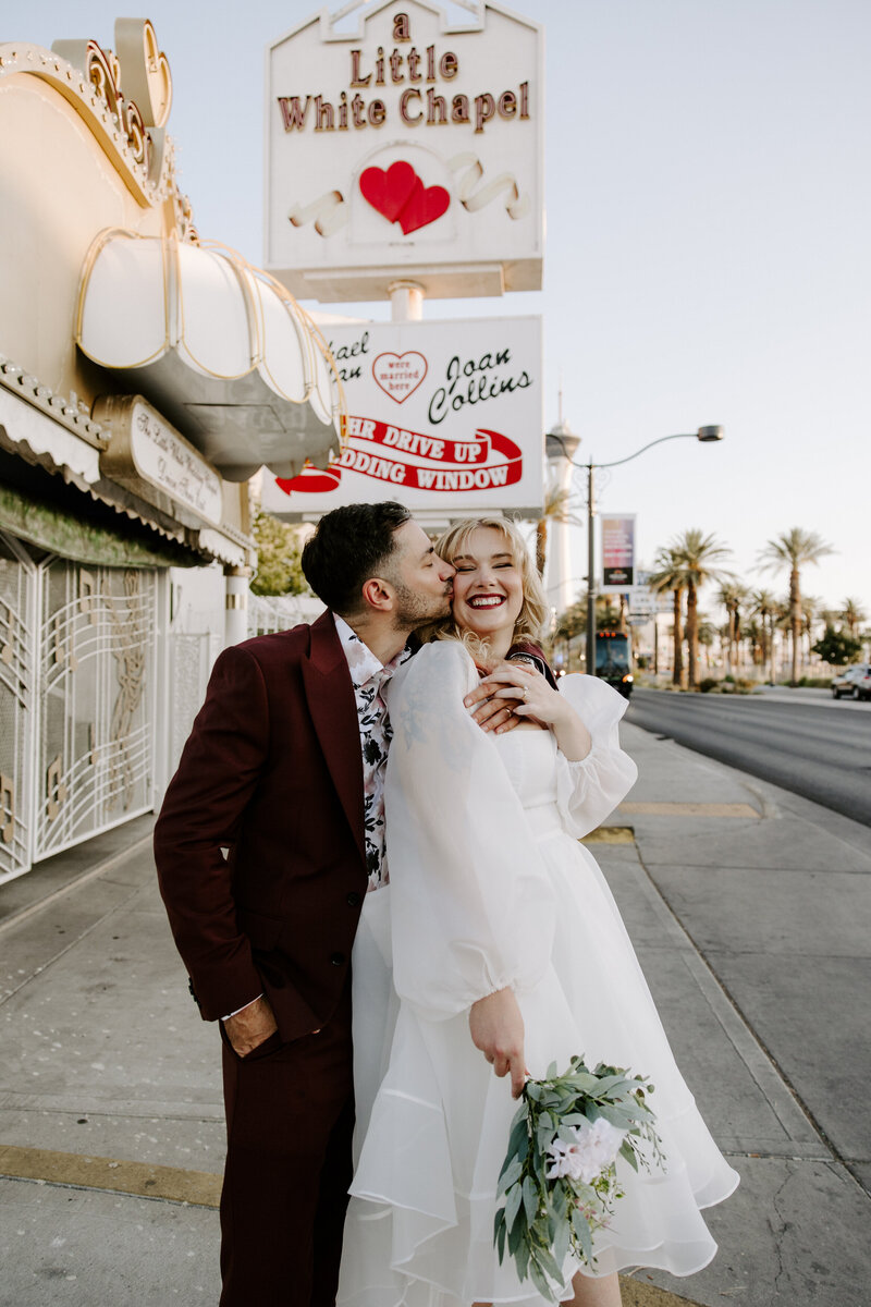 A couple poses with classic Vegas signs behind them