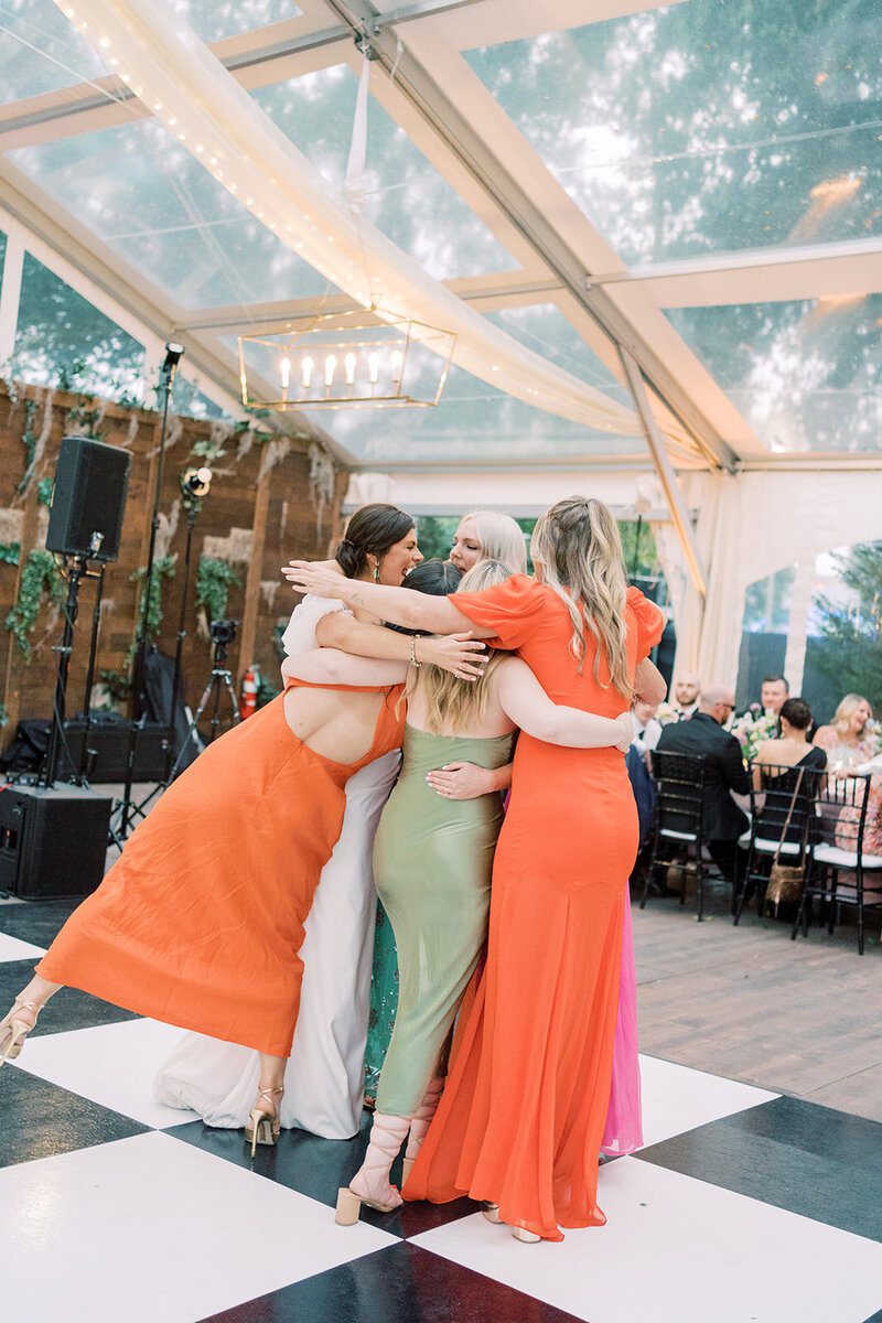 Bride hugging girls in colorful dresses on wedding dance floor